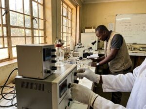 Researcher adjusting precision scientific instruments in developing country laboratory with natural window lighting